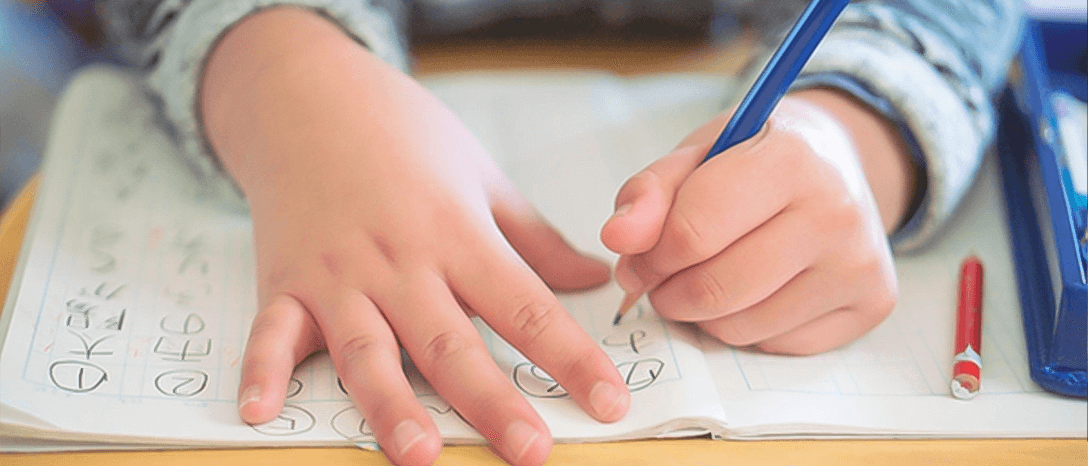 prváčik so zošitom na stole